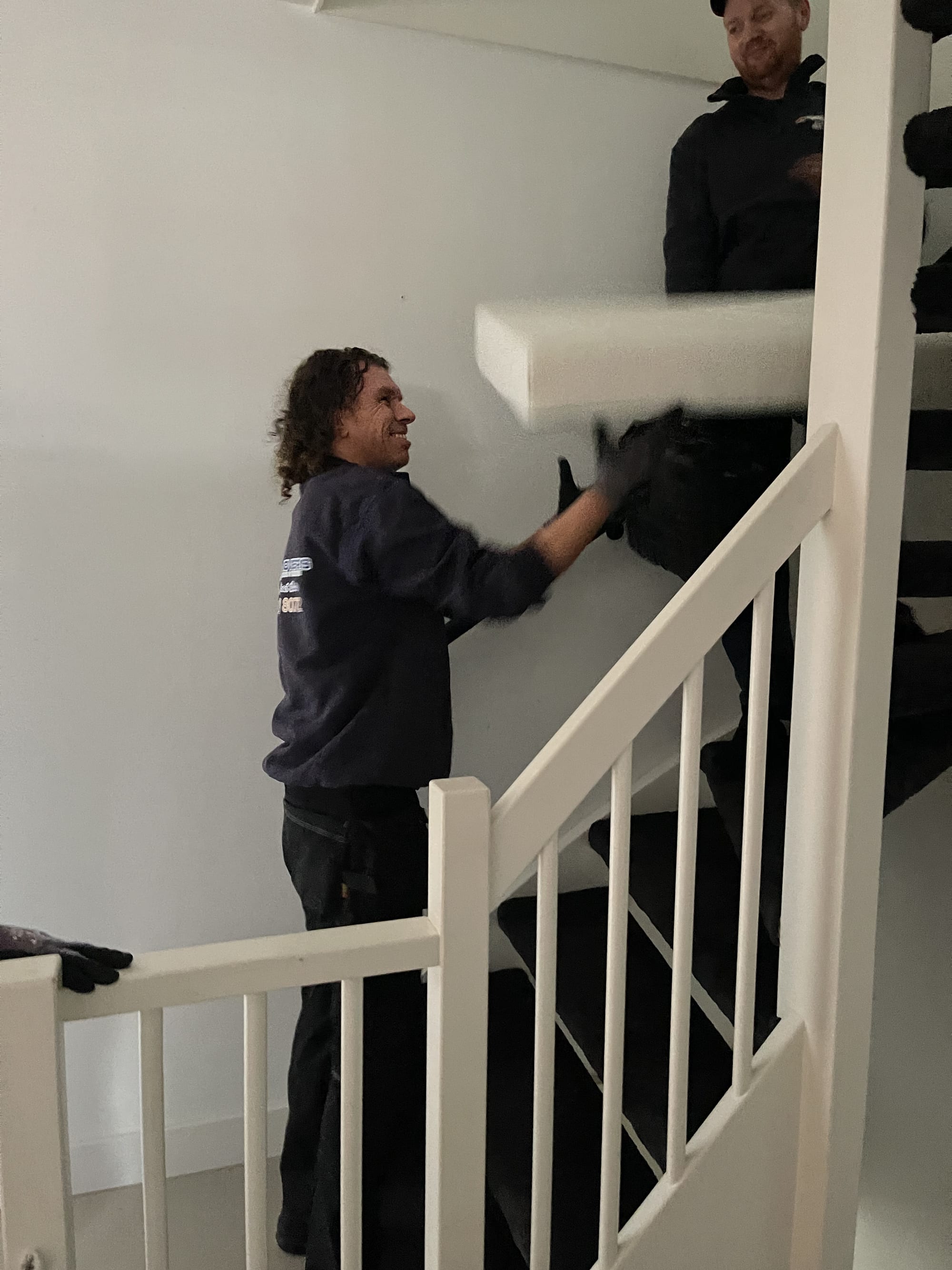 Verhuizers dragen een matras voorzichtig de trap af