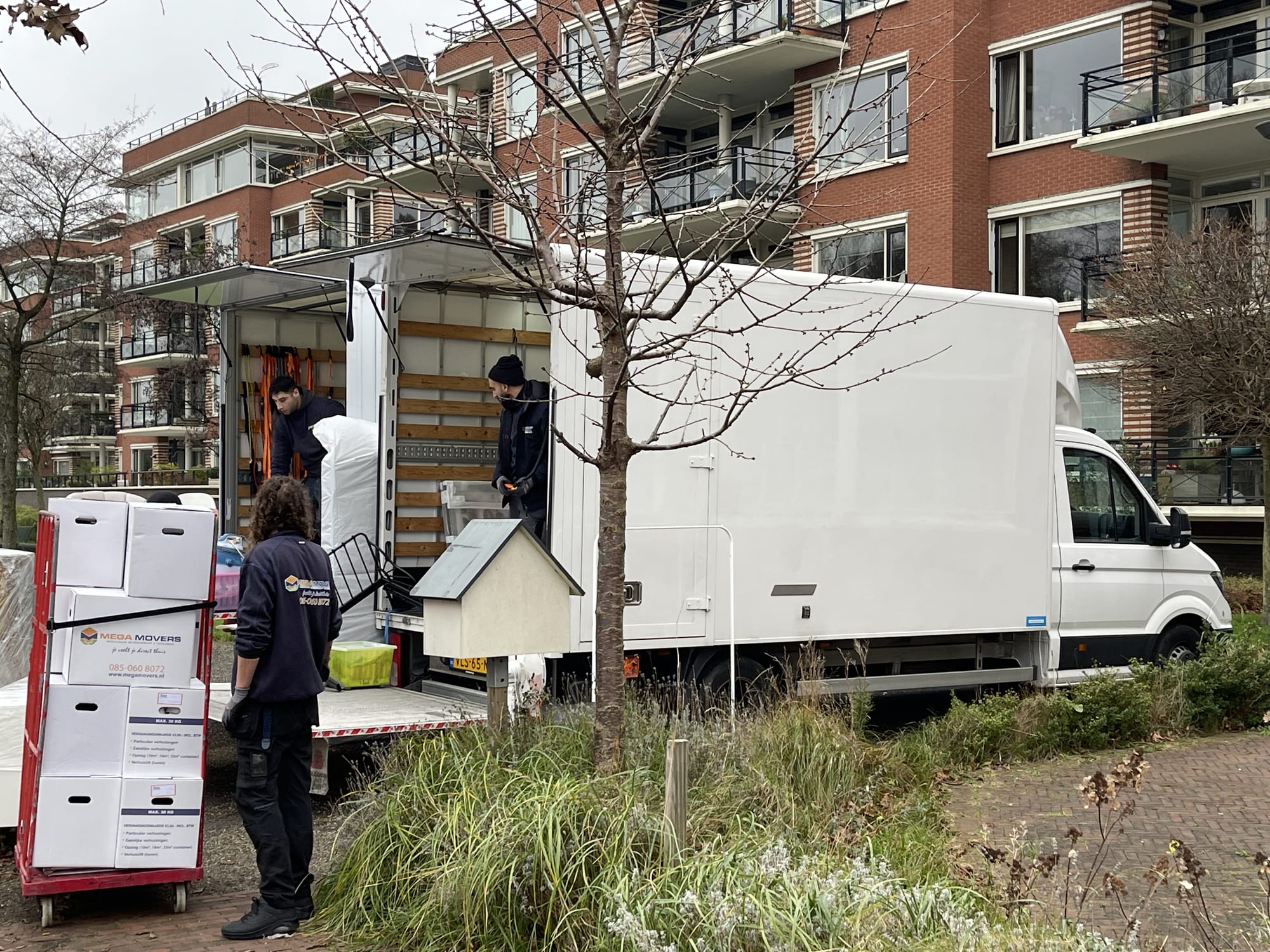 Verhuizers laden de verhuiswagen in bij een appartement